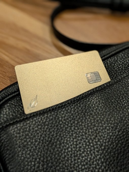 Gold Robinhood card resting on a black leather bag